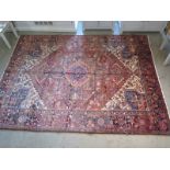 A hand knotted, woollen Heriz rug with red ground, approx. 291cm x 220cm, in good condition