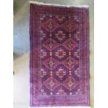 A hand knotted woollen rug, with a red field, 146cm x 85cm - some wear mainly to fringes