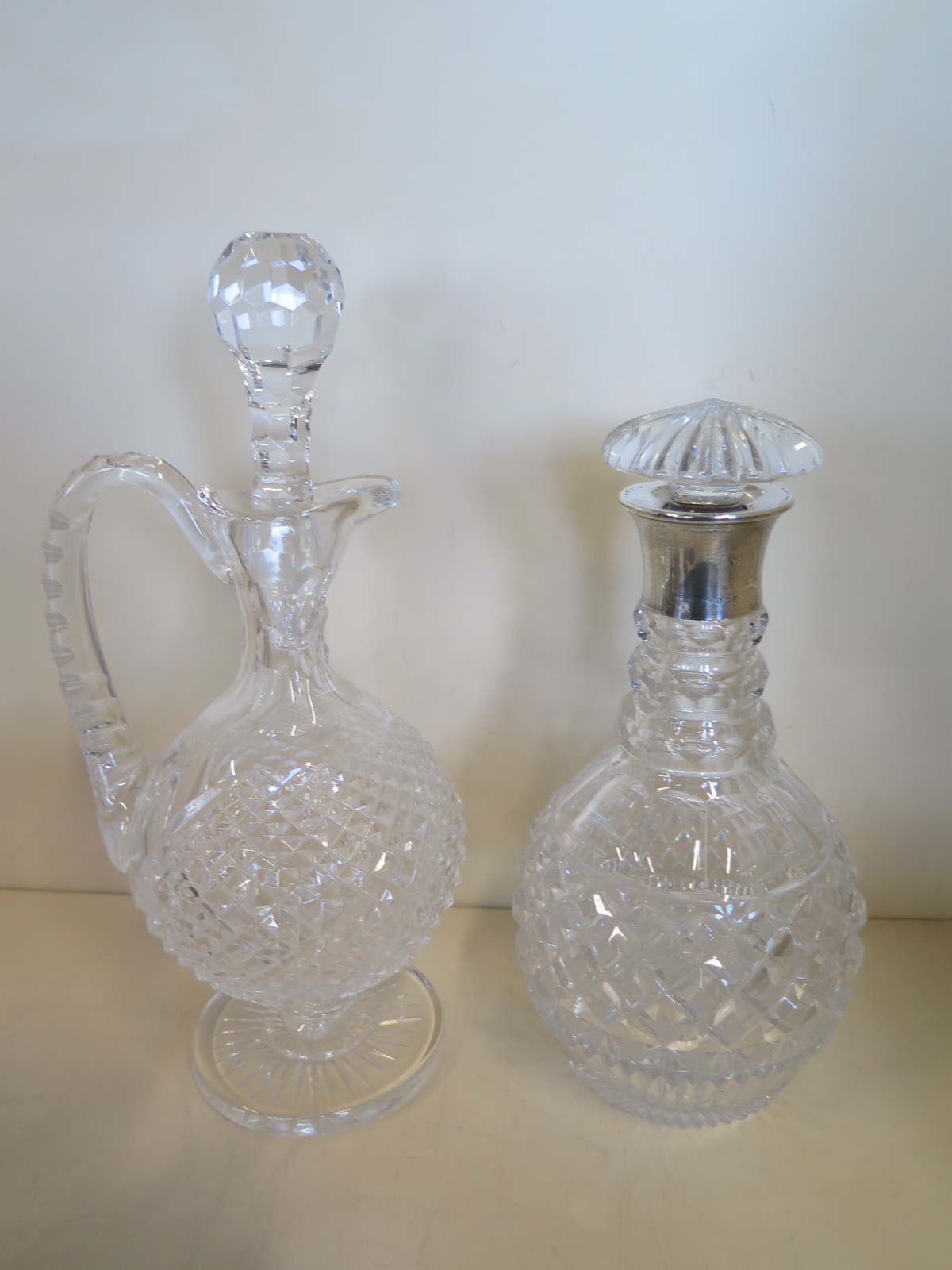 A cut glass decanter with a silver collar and a cut glass claret jug, 32cm tall - both generally