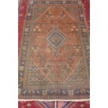 A hand knotted woollen rug with a red field, some wear and repair - 197cm x 125cm