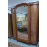 A continental walnut triple wardrobe armoire with a central mirrored door enclosing a shelved