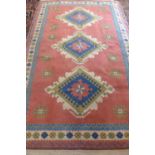 A hand knotted woollen rug with pale red ground and geometric designs, approx 281cm x 181cm -