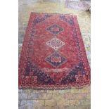 A hand knotted woollen rug with a red field, colours bright, some general wear mainly to edges - 2.