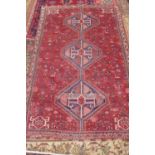 A hand knotted woollen rug with a red field, colours bright, some patches of wear - 276cm x 182cm