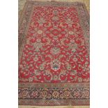 A machine made woollen rug with a red field - 295cm x 200m - some general usage wear, colours bright