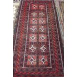 A small hand knotted woollen rug with red ground, approx 217cm x 110cm - with wear throughout