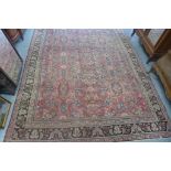 A hand knotted woollen rug from Iran with a red field - 376cm x 288cm - general patches of wear