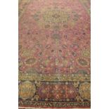 A large hand knotted woollen rug, with pink ground, approx 558cm x 368cm - with some wear, otherwise