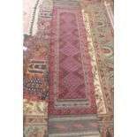 A hand knotted woollen runner with a red field - 265cm x 61cm