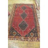 A hand knotted woollen rug from Iran with a red field, colours bright, some wear mainly to edges -