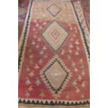 A hand knotted woollen Kelim rug with three central diamonds, approx 275cm x 132cm - with wear