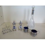 Two silver salts and two silver peppers and a small silver toast rack and silver rim bottle, total