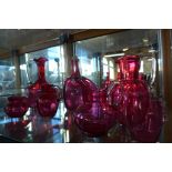 Seven pieces of cranberry glassware, two medium jugs and a glass good, rest have damage or repair