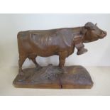 A well carved wooden figure of a cow with large bell collar on a naturalistic base, probably Swiss