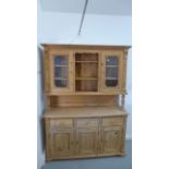 A modern pine dresser, the top with two glazed doors over the base with three drawers and three