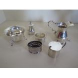 A silver cream jug and sugar bowl, a silver mustard, pepper, napkin ring and a silver surround,