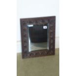 A 1920s bevel-edged mirror in a carved oak frame - 42cm x 35cm - in polished condition