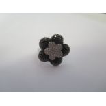 An 18ct white and black diamond daisy ring, sey in white gold, 20mm wide, size L/M approx 6.8 grams,