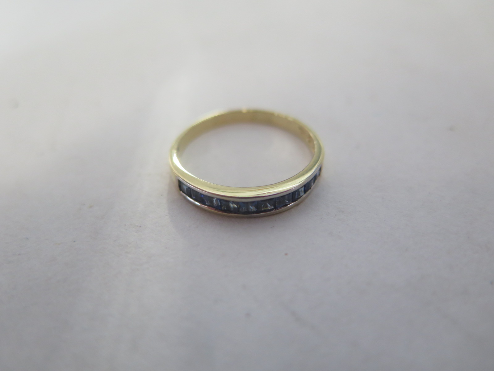 An 18ct yellow gold band ring, set with nine sapphires, ring size Q, approx 2.2 grams, in good