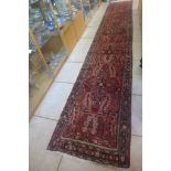 A hand knotted woollen Iranian runner with red field, approx 503cm x 82cm