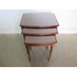 A nest of three bow fronted rectangular side tables with tapered fluted legs and inset glass tops,