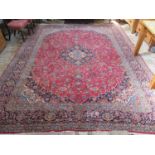 A hand knotted large Kashan rug with red ground central field and blue ground border, approx 374cm x