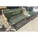 A pair of garden benches with ornate cast iron ends and wooden slat seats, each approx 126cm wide