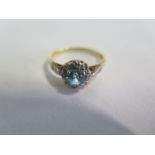 An 18ct yellow gold ring, with a blue stone surrounded by small diamonds, size Q, approx 3.6