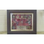 A display of framed sewing collectables in brown carved frame, including cranberry glass and