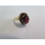 A 9ct yellow gold garnet ring with a central garnet surrounded by 14 small garnets, ring size H,