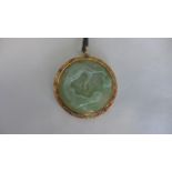 A carved jade pendant in a 14ct yellow gold mount - 5.5cm wide - in good condition