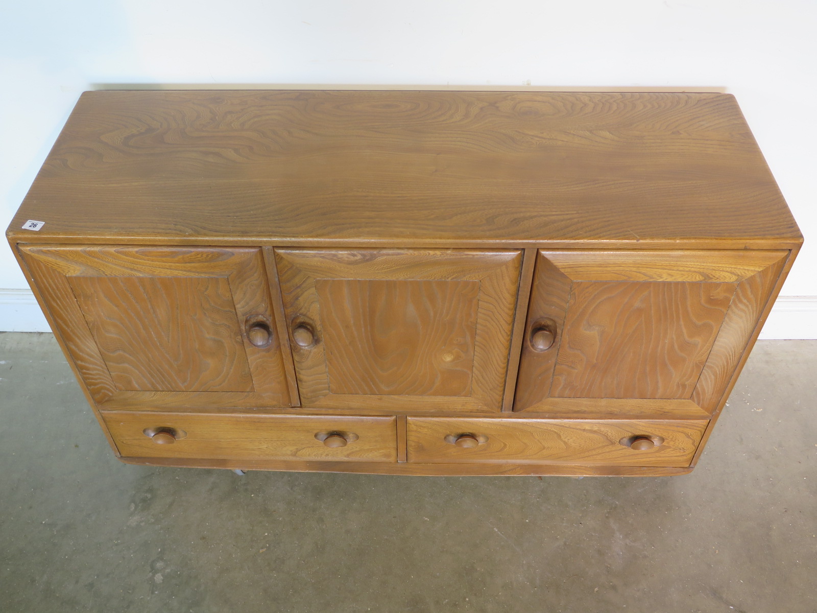 An Ercol blonde elm and beech sideboard with three cupboard doors over three drawers, missing its - Image 2 of 4