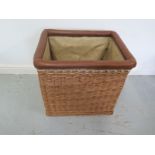 A wicker log bin with a leather rim and internal cloth liner, 68cm wide x 62cm H x 54cm D