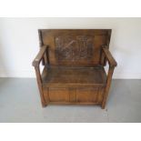 A 1930's carved oak monks bench with a lift up seat, 93cm wide