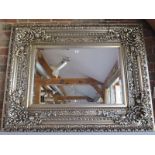 A contemporary bevelled edged over mantle mirror with ornate silvered frame, approx 120cm x 95cm -