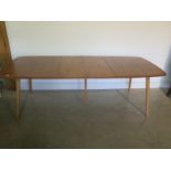 An Ercol blonde elm and beech extending table with a folding two section leaf raised on five