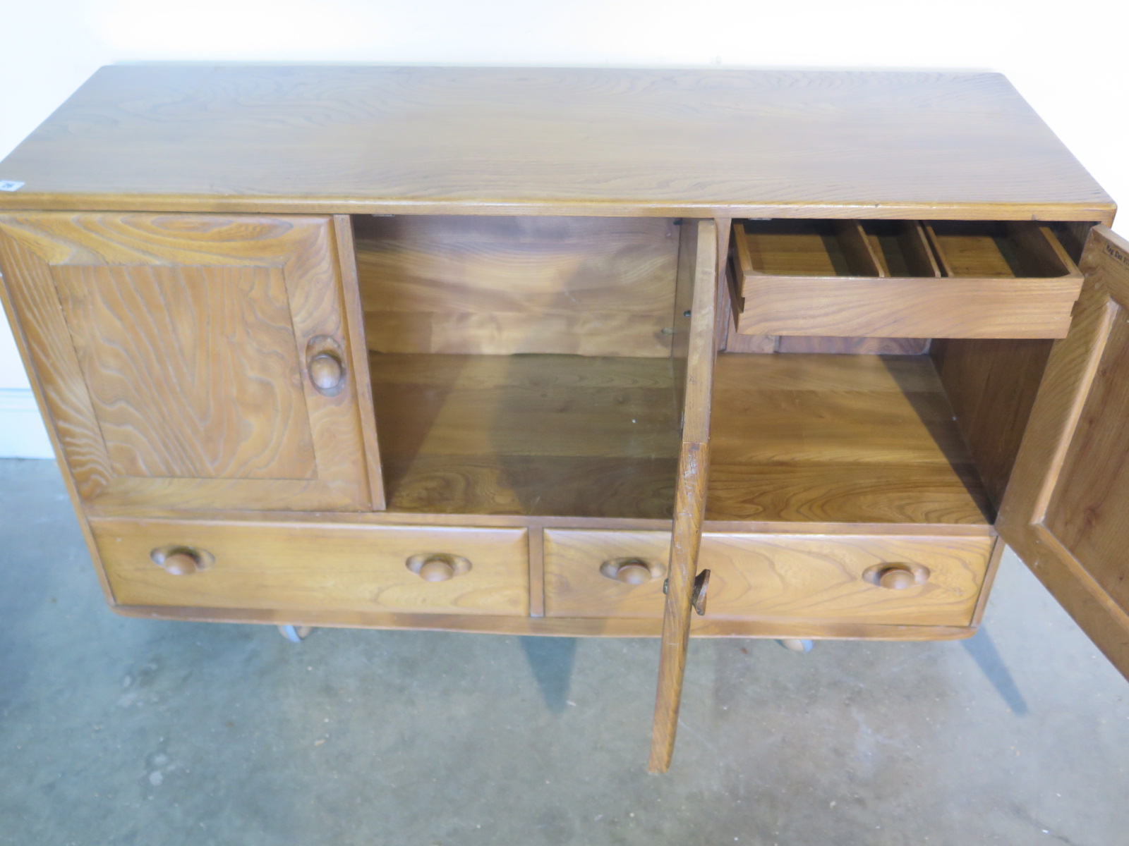 An Ercol blonde elm and beech sideboard with three cupboard doors over three drawers, missing its - Image 4 of 4