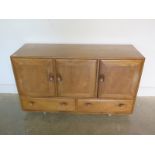 An Ercol blonde elm and beech sideboard with three cupboard doors over three drawers, missing its