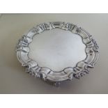 A silver waiter with scalloped edge on three feet, approx 7.7 troy oz, approx 16cm diameter - in