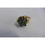 A yellow metal pentagonal cluster eleven stone emerald ring, size M, centre 4mm surrounded by five