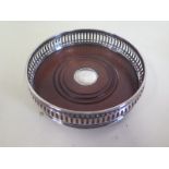 A pierced silver coaster with wood base and silver button, approx 13cm diameter, in good condition