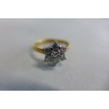 An 18ct yellow and white gold diamond daisy cluster ring, the central brilliant cut diamond is set