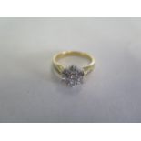 An 18ct yellow gold seven stone diamond cluster ring with small diamonds to the shoulder, head is