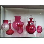 A collection of six cranberry jugs, a decanter and a perfume bottle, one jug cracked otherwise