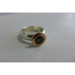 A 9ct white and rose gold green sapphire solitaire ring by Debra Fallowfield, the round cut green