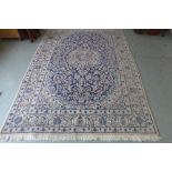 A hand knotted woollen rug with a cream and blue field, 310cm x 196cm