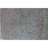 A large hand knotted woollen rug, with a light blue field, some wear but reasonably good, one end