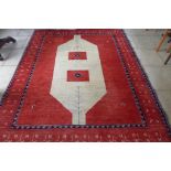 A hand knotted red ground rug with caucasian central field, borders decorated with zoomorphic