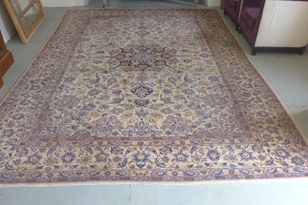 A hand knotted woollen rug with a cream field and foliate design 410cm x 290cm