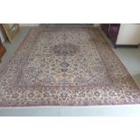 A hand knotted woollen rug with a cream field and foliate design 410cm x 290cm